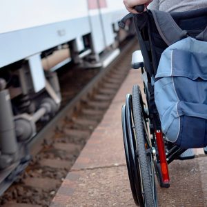 A person being pushed in a wheelchair along a train platform